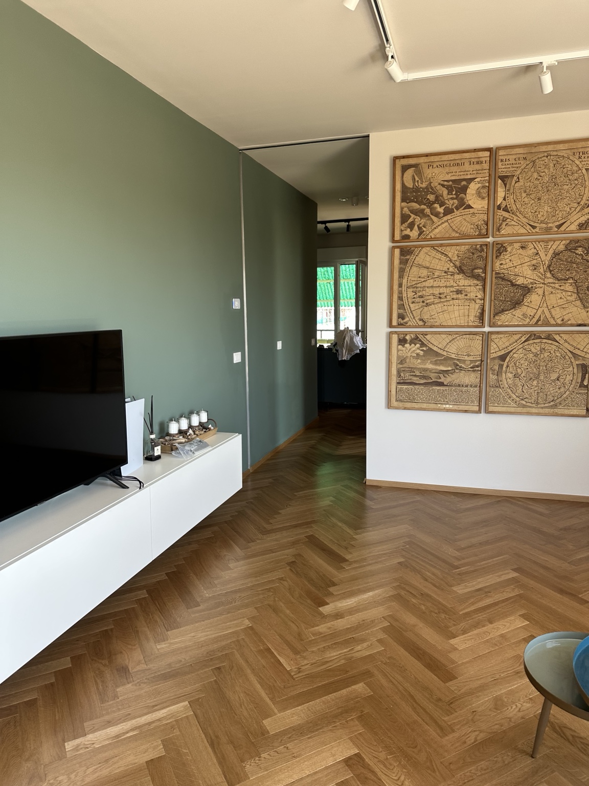 Zona living: parete verde e pavimentazione a spina