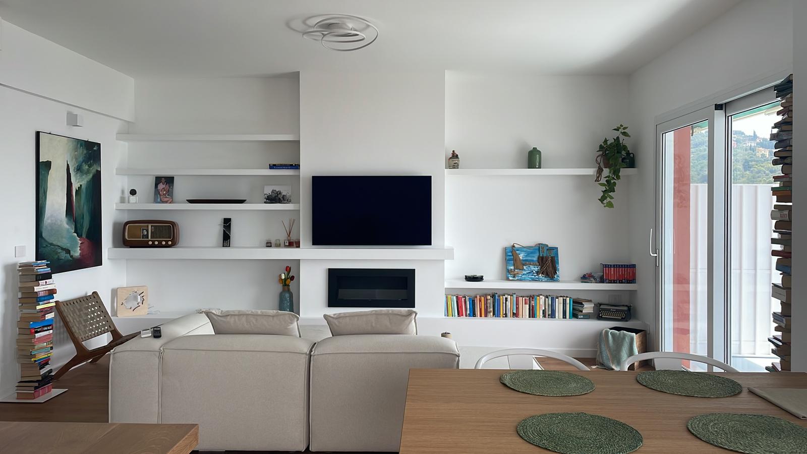 Zona living: parete attrezzata e finiture bianche